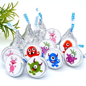 Little monster theme first birthday favors shown on a set of foil-wrapped chocolate kisses.