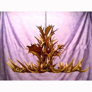 Peut inclure: Un grand lustre en bois de cerf avec de multiples branches et lumières. Le lustre est fait de bois de cerf naturel et a un aspect rustique et naturel.
