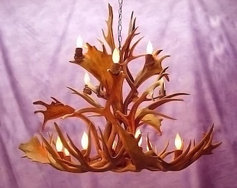 May include: A large antler chandelier with multiple light bulbs. The chandelier is made of natural antlers and has a rustic, natural look.
