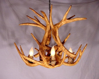 May include: A rustic chandelier made from antlers with a natural brown finish. The chandelier has four light bulbs and is hanging from a chain.
