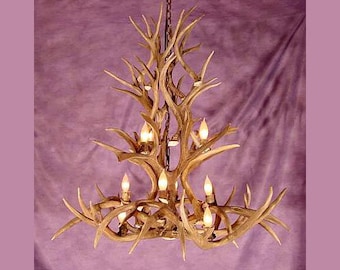 Può includere: Un lampadario realizzato con un grande corno di cervo naturale con più rami. Il corno di cervo è lucidato e ha un colore marrone chiaro. Il lampadario ha più lampadine, ciascuna con una luce bianca calda.