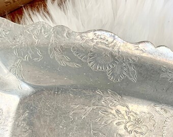 May include: A silver serving tray with a scalloped edge and an embossed floral design.