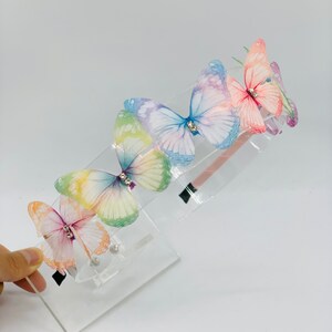 Pu&ograve; includere: Un cerchietto con cinque farfalle iridescenti e strass. Il cerchietto &egrave; in plastica trasparente.