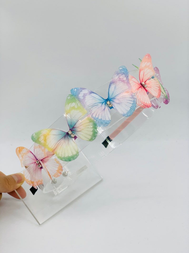 Pu&ograve; includere: Un cerchietto con cinque farfalle iridescenti e strass. Il cerchietto &egrave; in plastica trasparente.