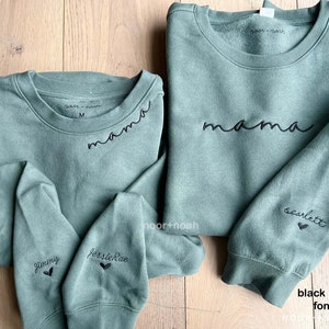 May include: Three green sweatshirts with black embroidered text. The largest sweatshirt says "mama" on the front and "scarlett" on the sleeve. The smaller sweatshirts have names and hearts on the sleeves. The text is in a black thread font 11.