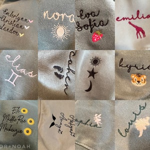 May include: A collage of 10 embroidered sweatshirts with various names, designs, and symbols. The sweatshirts are all a light blue color. Some of the designs include a sun, a star, a moon, a strawberry, a giraffe, a tiger, a sunflower, a fairy, and a set of footprints.