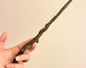 May include: A dark brown wooden wand with a twisted, gnarled design. The wand is approximately 35 cm long and has a pointed tip.