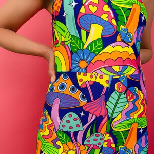 May include: A colorful jumpsuit with a psychedelic print featuring mushrooms, butterflies, flowers, and a frog. The background is a dark blue.