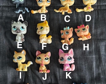 May include: A collection of 14 plastic cat figurines, each with different colors, patterns, and poses. The cats are arranged in rows, labeled with letters A through N.