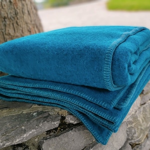 Könnte beinhalten: Eine gefaltete blaugrüne Decke mit einem gesteppten Rand. Die Decke ist aus einem weichen, flauschigen Material gefertigt und perfekt, um sich an einem kalten Tag warm zu halten.