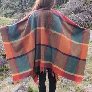 May include: A large, colorful plaid poncho with fringe. The poncho is made of a soft, warm fabric and features a variety of colors, including red, orange, yellow, green, and brown.