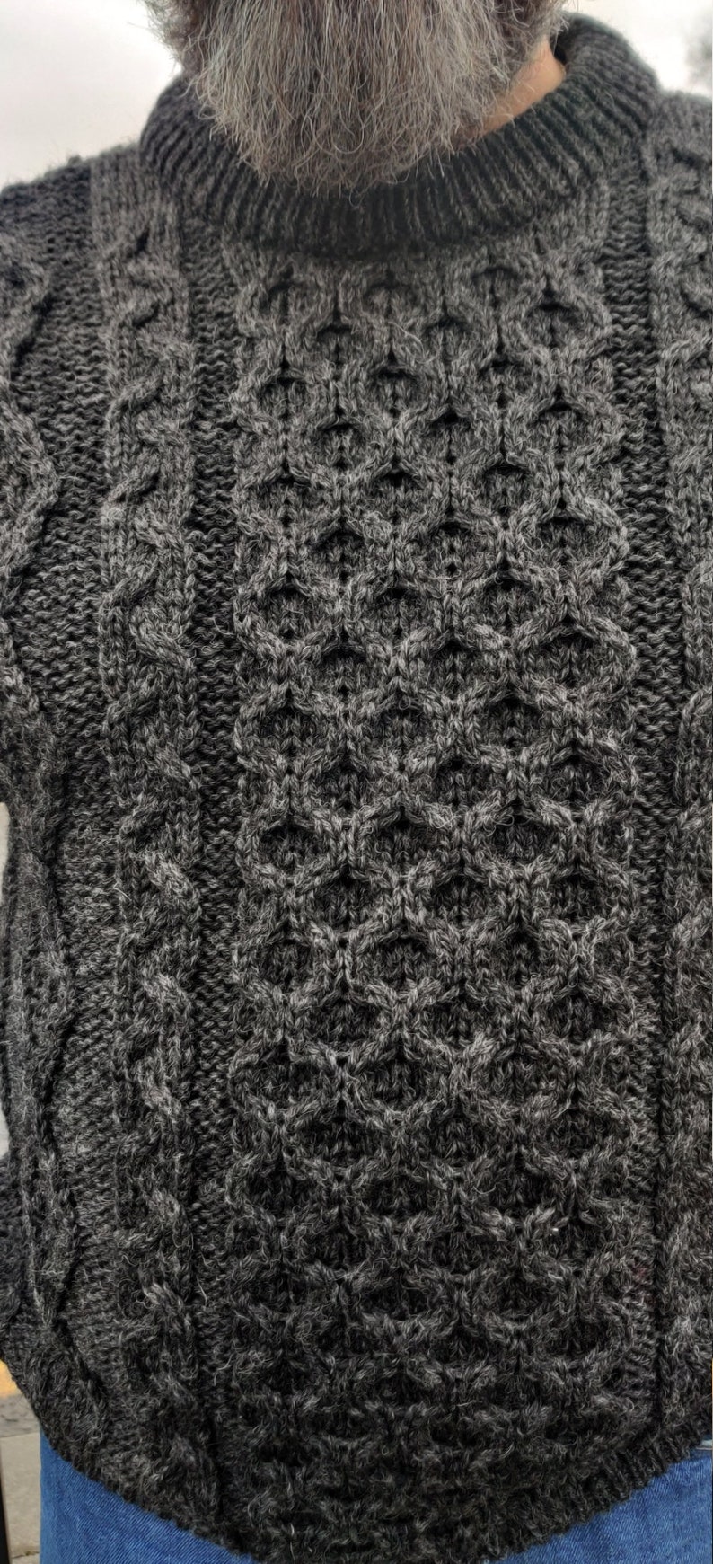 May include: A dark gray cable knit sweater with a textured pattern.