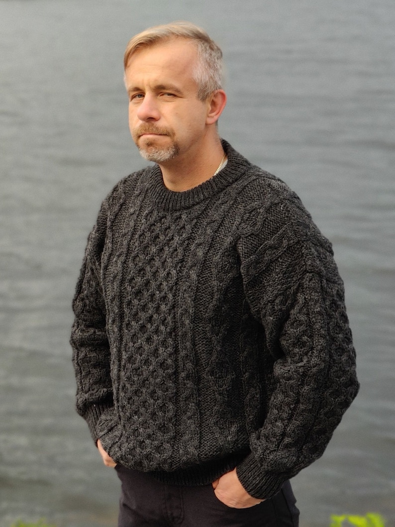 May include: A dark gray cable knit sweater with a crew neck.