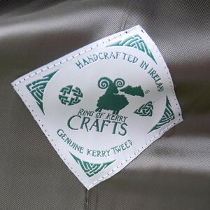 May include: White label with green text and a green sheep illustration. The label reads "Handcrafted in Ireland", "Ring of Kerry Crafts", and "Genuine Kerry Tweed".