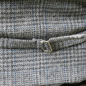 May include: The back of a gray and blue patterned vest with a silver buckle.