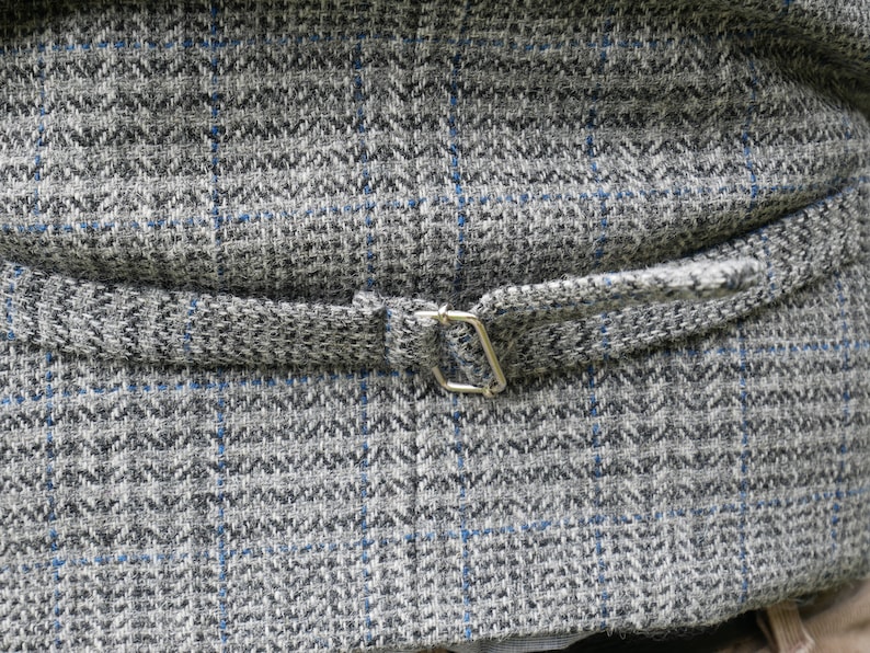 May include: The back of a gray and blue patterned vest with a silver buckle.