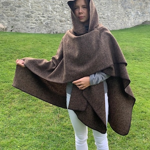 May include: A brown hooded cape with a black trim. The cape is made of a soft, textured fabric and has a relaxed fit.