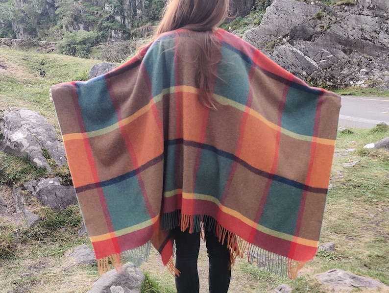 May include: A large, colorful plaid poncho with fringe. The poncho is made of a soft, warm fabric and features a variety of colors, including red, orange, yellow, green, and brown.