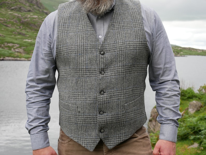 May include: A gray and black plaid vest with five buttons. The vest is made of a tweed fabric and has a classic style.