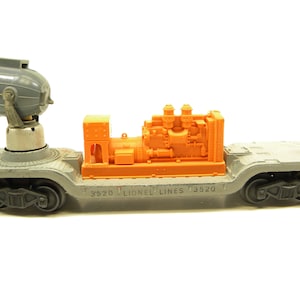 Puede incluir: Un vagón de tren modelo Lionel Lines gris y naranja con un faro giratorio en la parte delantera y un generador en la parte trasera. El vagón está etiquetado con "3520 Lionel Lines 3520".