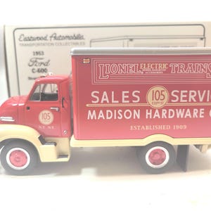 Könnte beinhalten: Ein rot-cremefarbener Modell-LKW Ford C-600 von 1953 mit der Marke "Lionel Electric Trains". Der LKW trägt die Aufschriften "Sales" und "Service" sowie "Madison Hardware Co." und "Established 1909". Das Modell ist ein Sammlerstück.