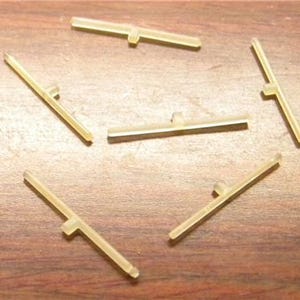 May include: Six translucent, beige plastic T-shaped pieces, likely for model building or crafts.