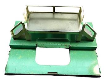 May include: A green metal toy platform with a metal cage on top. The platform has a rectangular opening in the center.