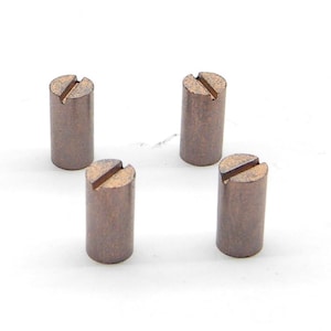 May include: Four brown metal cylinder shaped objects with a slot cut into the top. The objects are arranged in a square pattern on a white surface.