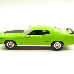 Könnte beinhalten: Ein grüner Plymouth Barracuda von 1970 mit einem schwarzen Streifen auf der Motorhaube und einem schwarzen Heckspoiler. Das Auto hat einen 440-6 Motor und ein GTX Emblem an der Seite.