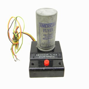 Puede incluir: Silbato de vapor American Flyer con base negra y botón rojo. El silbato está conectado a un generador de silbato de aire de plata con cables.