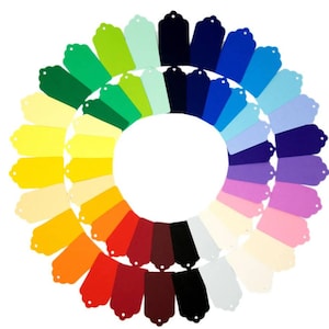May include: A circular display of coloured gift tags, arranged in a gradient. The tags, in shades of yellow, green, blue, purple, and red, have a scalloped top and a hole for stringing. The arrangement is set against a white background.