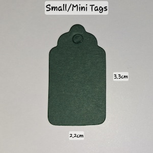 May include: A dark green tag with a decorative top and a small hole. The tag is 2.2 cm wide and 3.3 cm tall. The text "Small/Mini Tags" is at the top.