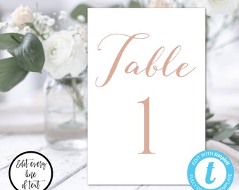 May include: White card with the text "Table 1" in a cursive font. The text is in a light pink color.