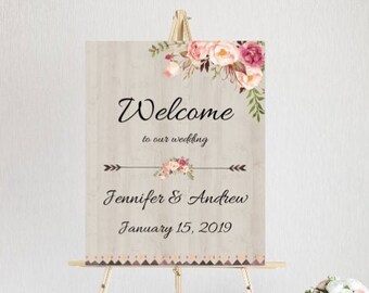 May include: A welcome sign for a wedding with a rustic wood background and floral design. The sign says "Welcome to our wedding" with the couple's names and wedding date. The sign is 16 inches by 20 inches.