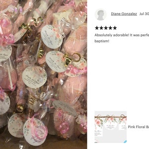 K&ouml;nnte beinhalten: Rosa und wei&szlig;e florale Taufgeschenkanh&auml;nger mit goldener Akzent. Die Anh&auml;nger sind mit einem rosa Band gebunden und an einer durchsichtigen Cellophant&uuml;te befestigt, die einen rosa Lutscher enth&auml;lt. Die Anh&auml;nger haben den Text "Miracle of Christ" aufgedruckt.