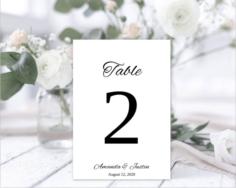 May include: White card with black text that reads "Table 2 Amanda & Justin August 12, 2020".