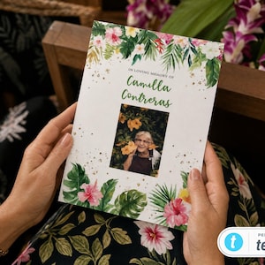 Könnte beinhalten: Eine rechteckige Trauerprogrammkarte mit einem tropischen Blumenrand in Aquarelloptik, bestehend aus grünen Palmenblättern und rosa Hibiskusblüten. Der Text lautet In Loving Memory of Camilla Contreras über einem zentralen Foto einer älteren Person.
