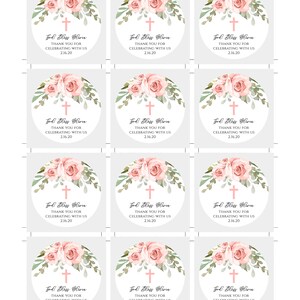 K&ouml;nnte beinhalten: Zw&ouml;lf runde Gef&auml;lligkeits-Etiketten mit wei&szlig;em Hintergrund und rosafarbenem Blumendesign. Jedes Etikett zeigt ein Kreuz und den Text "God Bless Olivia" mit dem Datum "2.16.20".