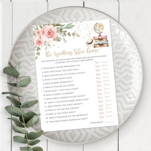 Puede incluir: Un juego de boda imprimible con un diseño floral rosa. El juego se llama "The Wedding Shoe Game" y hace 15 preguntas sobre la pareja. Las preguntas están diseñadas para ser respondidas por la pareja sosteniendo sus zapatos.