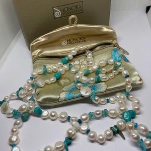 May include: A white pearl necklace and bracelet set with turquoise and blue accents. The set is in a beige satin pouch with the Honora Collection logo.