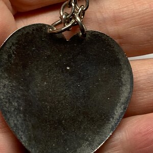 May include: A silver heart-shaped keychain pendant with a chain. The pendant has a worn, textured surface. The keychain is a simple, classic design.