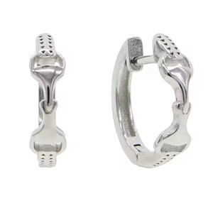 May include: A pair of silver horseshoe hoop earrings. The earrings are made of metal and have a polished finish.
