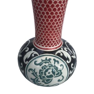 May include: A ceramic vase with a red and white patterned top and a blue and white floral design on the bottom.