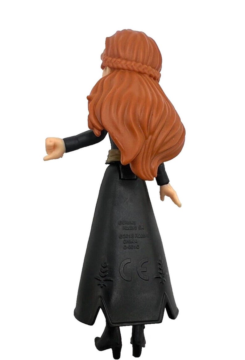 May include: A plastic figurine of a character with long, flowing auburn hair and a braided crown. The figure wears a black dress with a flared skirt and black boots. The back of the figure is visible, with the arms extended.