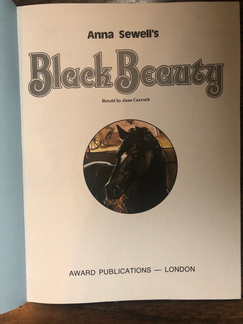 May include: A book cover with the title "Black Beauty" by Anna Sewell, retold by Jane Carrruth. The cover features a black horse with a brown mane and tail, eating hay in a stable.