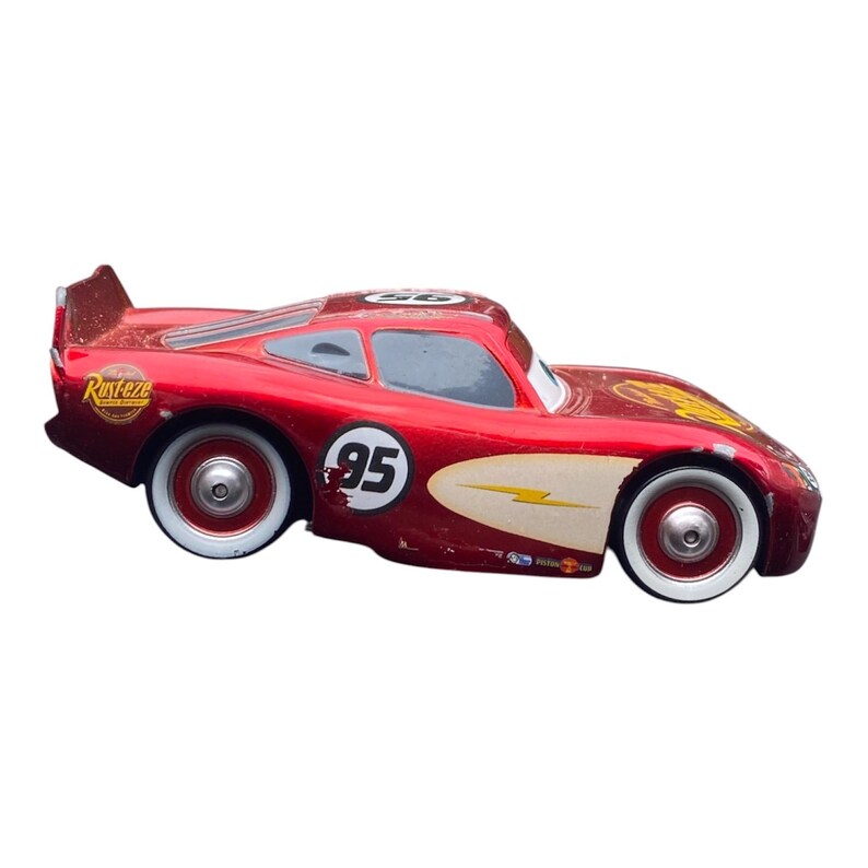 Peut inclure: Une voiture de course jouet rouge avec des pneus &agrave; flancs blancs. La voiture porte le num&eacute;ro 95 sur le c&ocirc;t&eacute; et un motif d'&eacute;clair. La voiture porte le mot "Rusteze" sur le c&ocirc;t&eacute;.