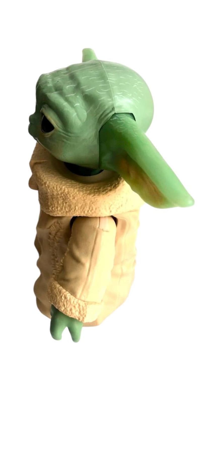 May include: A green and beige plastic toy figure of a character from the Star Wars franchise. The figure is wearing a brown coat with a fur trim.