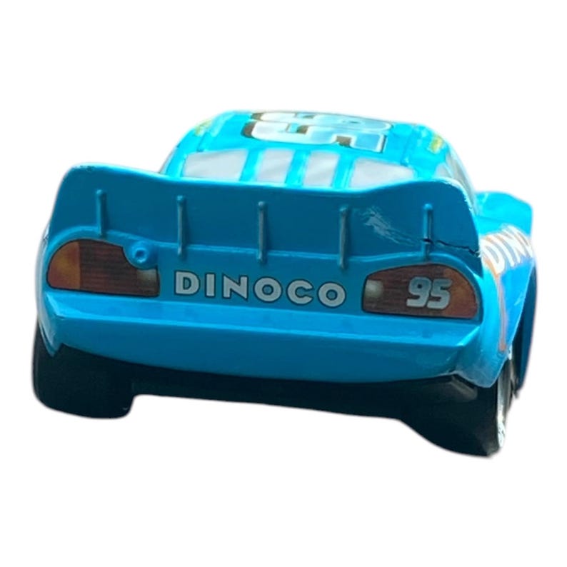 May include: A blue toy car with the number 95 on the back. The car has the word "DINOCO" printed on the back. The car has a spoiler and a detailed design.