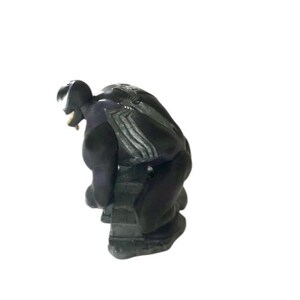 May include: Black and gray Venom action figure in a crouching pose. The figure is made of plastic and has a detailed sculpt.