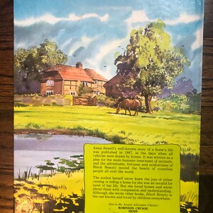 May include: A vintage book cover with a watercolor illustration of a house and a horse in a green field. The text on the cover reads "Anna Sewell's well-known story of a horse's life was published in 1887, in the days when all vehicles were drawn by horses. It was written as a plea for the more humane treatment of animals, and the adventures, fortunes and misfortunes of Black Beauty moved the hearts of countless people all over the world."